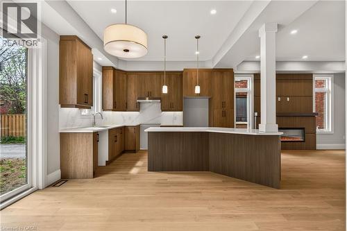 Spacious kitchen featuring warm wood-finish cabinetry, light countertops, and a large island with an integrated sink - 279 Hess Street S, Hamilton, ON - Indoor Photo Showing Kitchen