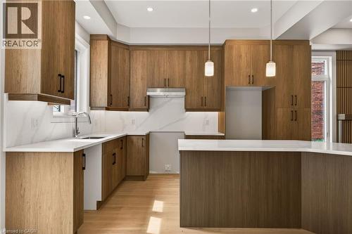 Kitchen featuring light wood-finish cabinetry, white countertops with veining, a stainless steel sink with a gooseneck faucet, light wood-finish flooring, and recessed lighting - 279 Hess Street S, Hamilton, ON - Indoor Photo Showing Kitchen