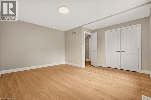Spacious room featuring wood-finish flooring, light neutral wall tones, white baseboards, and a contemporary ceiling light fixture - 279 Hess Street S, Hamilton, ON - Indoor Photo Showing Other Room