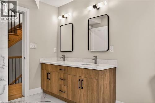 Dual vanity featuring a wood-finish cabinet with black hardware, white countertop, and integrated sinks - 279 Hess Street S, Hamilton, ON - Indoor Photo Showing Bathroom
