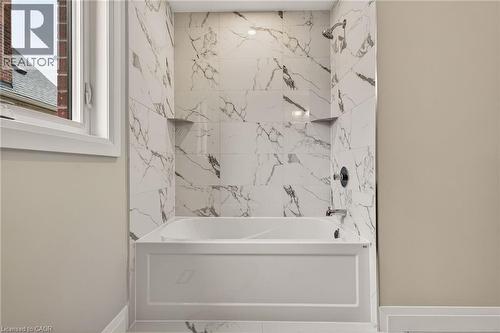 Bathtub with white paneling and a shower featuring large-format marbled tile - 279 Hess Street S, Hamilton, ON - Indoor Photo Showing Bathroom