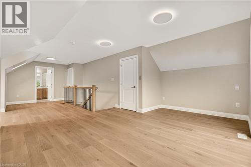 Spacious open-concept room featuring wide-plank wood-finish flooring, recessed lighting, and a contemporary wood and metal staircase railing - 279 Hess Street S, Hamilton, ON - Indoor Photo Showing Other Room