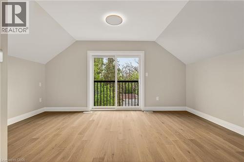 Room featuring wood-finish flooring, vaulted ceilings, and a sliding glass door leading to a balcony with black metal railings - 279 Hess Street S, Hamilton, ON - Indoor Photo Showing Other Room