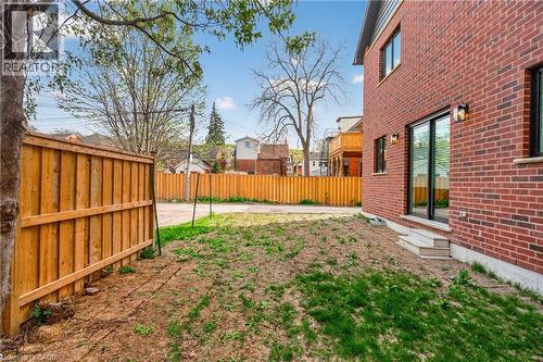 Brick exterior featuring an expansive rear yard, sliding glass door access, two exterior wall sconces, and a wood privacy fence - 279 Hess Street S, Hamilton, ON - Outdoor