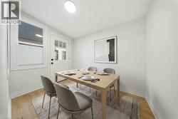 Dining area featuring wood-finish flooring, a white paneled door with glass inserts, and a white-framed window Virtually Staged - 
