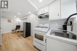 Efficient kitchen featuring white cabinetry, a gas range, stainless steel sink, and light-toned countertops - 