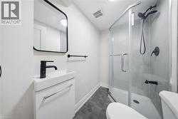 Bathroom featuring a glass-enclosed shower, dark geometric floor tiles, a wall-mounted vanity with integrated sink, matte black faucet, and a contemporary black-framed mirror - 