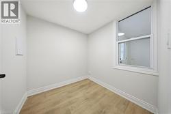 Compact room featuring wood-finish flooring, white baseboards, a single window, and a flush-mount ceiling light - 