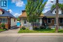 Single-story residence featuring a front yard with mature tree and landscaping, an asphalt driveway, a front porch with black railing, and a detached garage in the background - 463 Wellington Street N, Hamilton, ON  - Outdoor 