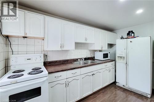 Kitchen featuring white cabinetry, a double basin sink, and wood-finish flooring - 463 Wellington Street N, Hamilton, ON - Indoor Photo Showing Kitchen With Double Sink