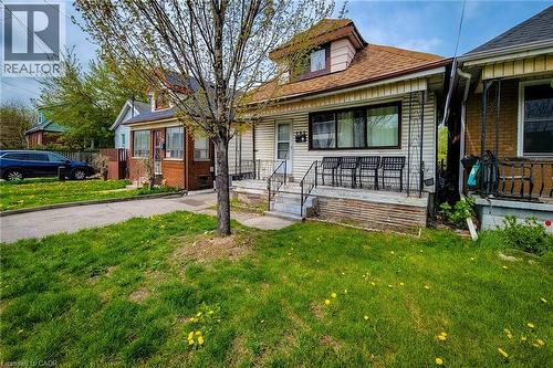 Single-family residence featuring a front porch with metal railings, a dormer window, and a paved driveway leading to a rear parking area - 463 Wellington Street N, Hamilton, ON - Outdoor