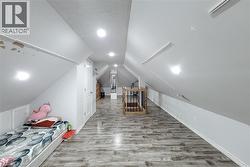 Spacious attic room featuring wood-finish flooring, recessed lighting, and sloped ceilings - 