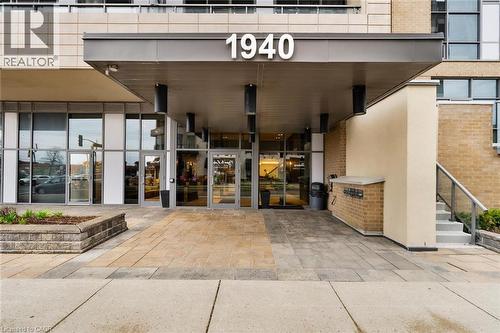 Building entrance featuring a contemporary portico, glass double doors, and a brick facade - 1940 Ironstone Drive Unit# 808, Burlington, ON - Outdoor