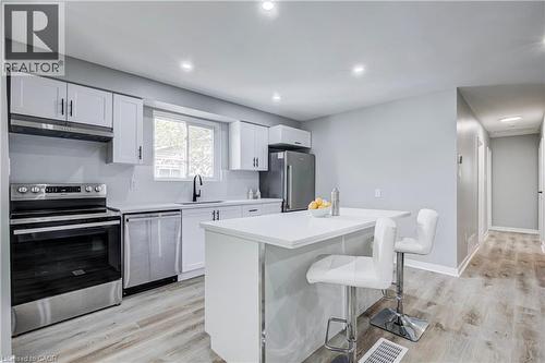 Contemporary kitchen featuring white cabinetry, stainless steel appliances, a center island with countertop seating, recessed lighting, and wood-finish flooring - 2367 Middlesmoor Crescent, Burlington, ON - Indoor Photo Showing Kitchen