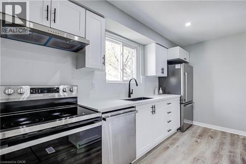 Kitchen featuring white cabinetry with matte black hardware, stainless steel appliances, a white countertop, and wood-finish flooring - 2367 Middlesmoor Crescent, Burlington, ON - Indoor Photo Showing Kitchen