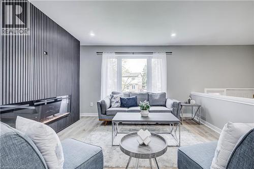 Living area featuring a modern linear fireplace with a vertical slat wall surround, recessed ceiling lighting, and light wood-finish flooring - 2367 Middlesmoor Crescent, Burlington, ON - Indoor Photo Showing Living Room