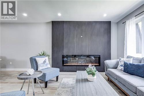 Living area featuring a floor-to-ceiling accent wall with vertical paneling and an integrated electric fireplace - 2367 Middlesmoor Crescent, Burlington, ON - Indoor Photo Showing Living Room With Fireplace