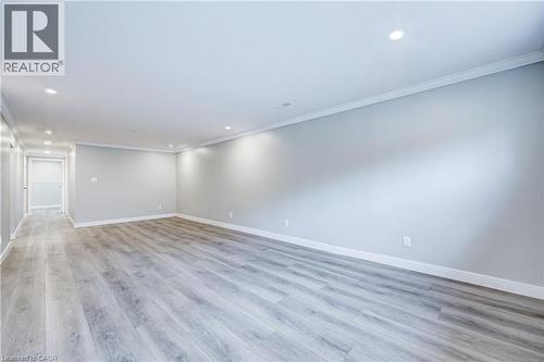 Spacious interior featuring wood-finish flooring, recessed lighting, crown molding, and light gray wall tones - 2367 Middlesmoor Crescent, Burlington, ON - Indoor Photo Showing Other Room