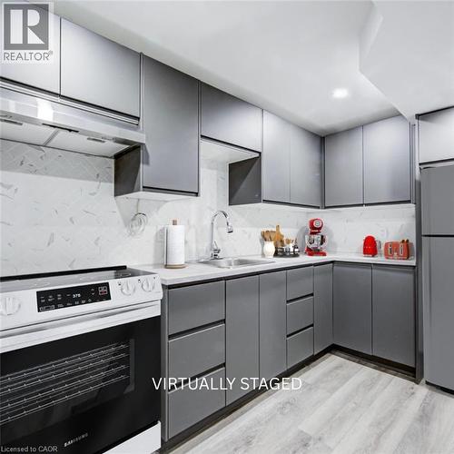 Contemporary kitchen featuring gray flat-panel cabinetry, a stainless steel range hood, and a white tile backsplash - 2367 Middlesmoor Crescent, Burlington, ON - Indoor Photo Showing Kitchen