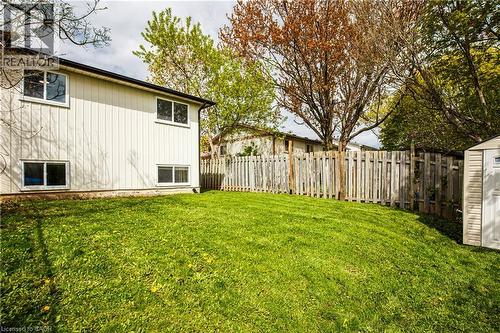 Spacious rear yard with a sloped lawn, bordered by a wooden privacy fence and mature trees - 2367 Middlesmoor Crescent, Burlington, ON - Outdoor