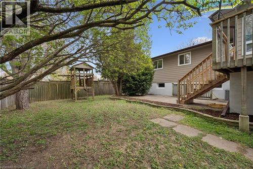 Spacious backyard featuring a wood privacy fence, mature trees, and a multi-level wooden play structure - 176 Woodville Place, Waterloo, ON - Outdoor