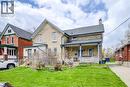 Brick exterior home featuring a covered front porch with white railing, a side entrance with wooden steps, a green lawn, and a paved driveway - 46 Shanley Street, Kitchener, ON  - Outdoor With Deck Patio Veranda 