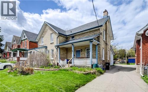 Brick exterior residence featuring a front porch with white railing, a side driveway, and a gabled roofline - 46 Shanley Street, Kitchener, ON - Outdoor With Deck Patio Veranda With Facade