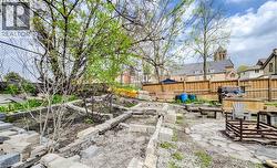 Spacious exterior area featuring a stone paver pathway, wood fencing, and mature trees - 