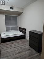 Interior room featuring wood-finish flooring, white walls, and a window with horizontal blinds - 