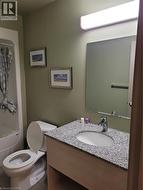Bathroom featuring a spacious vanity with a granite-style countertop and integrated sink, a modern chrome faucet, and a wall-mounted mirror - 