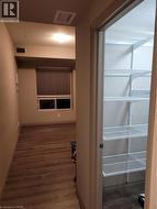 Entryway featuring wood-finish flooring, leading to a room with a window and horizontal blinds - 