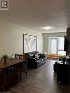 Open-concept living space featuring wood-finish flooring, light green wall paint, and a textured ceiling - 