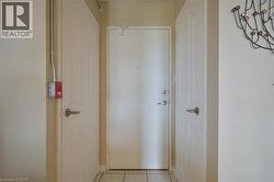 Entryway featuring a white door with brushed nickel hardware, surrounded by two panel doors with matching hardware, and light-toned tile flooring - 