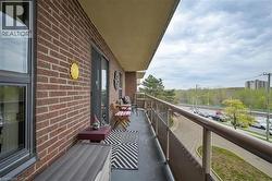 Spacious outdoor balcony featuring brick exterior, sliding glass door access, durable flooring, and a glass-paneled railing system - 
