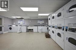 Spacious laundry facility featuring numerous front-load washers and stacked dryers - 