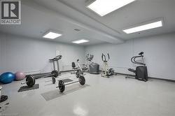 Dedicated fitness room featuring light grey walls, light grey flooring, and overhead panel lighting - 