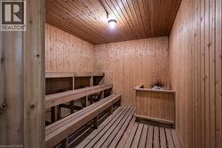 Wood-paneled sauna featuring tiered seating, slatted wood flooring, and a stone heater - 
