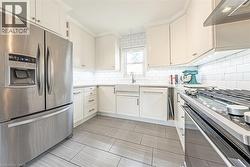 Modern kitchen featuring white shaker cabinetry and a tile backsplash - 