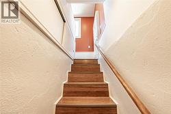 Staircase featuring wood-finish treads, a wood handrail, and textured white wall finishes - 