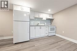 Compact kitchen equipped with white cabinetry, a light gray countertop, and a white tile backsplash - 