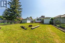 Expansive backyard featuring a lush lawn, a detached storage shed, a privacy fence, a raised garden bed, and a fire pit - 