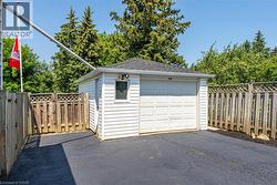 Detached single-car garage with white horizontal siding and a dark shingled roof - 