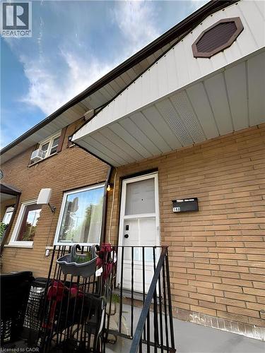 Brick exterior featuring a white entry door, black wrought iron railing, and prominent soffit with decorative octagon accent **Virtually Staged** - 148 Bishop Street S, Cambridge, ON 