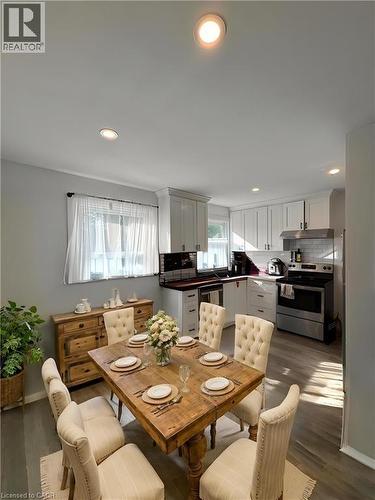Open-concept dining area featuring wood-finish flooring, recessed lighting, and a window with sheer white curtains **Virtually Staged** - 148 Bishop Street S, Cambridge, ON 
