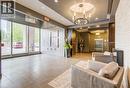 Spacious lobby featuring large format tile flooring, a circular recessed ceiling with a chandelier, floor-to-ceiling windows, and elevator access - 191 King Street S Unit# 607, Waterloo, ON 