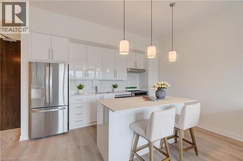 Contemporary kitchen featuring white cabinetry, a large stainless steel refrigerator, white countertops, and a white subway tile backsplash - 191 King Street S Unit# 607, Waterloo, ON 