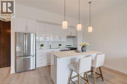 Contemporary kitchen featuring white cabinetry, a large stainless steel refrigerator, white countertops, and a white subway tile backsplash - 