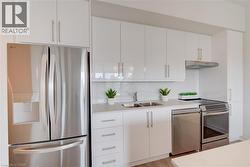 Modern kitchen featuring white cabinetry, a stainless steel refrigerator, a stainless steel dishwasher, a stainless steel range, and a dual basin sink - 
