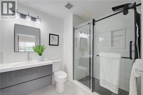 Modern bathroom featuring a floating vanity with a white countertop and integrated sink, a frameless rectangular mirror, and a three-light fixture with clear glass shades - 191 King Street S Unit# 607, Waterloo, ON 