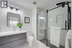 Modern bathroom featuring a floating vanity with a white countertop and integrated sink, a frameless rectangular mirror, and a three-light fixture with clear glass shades - 
